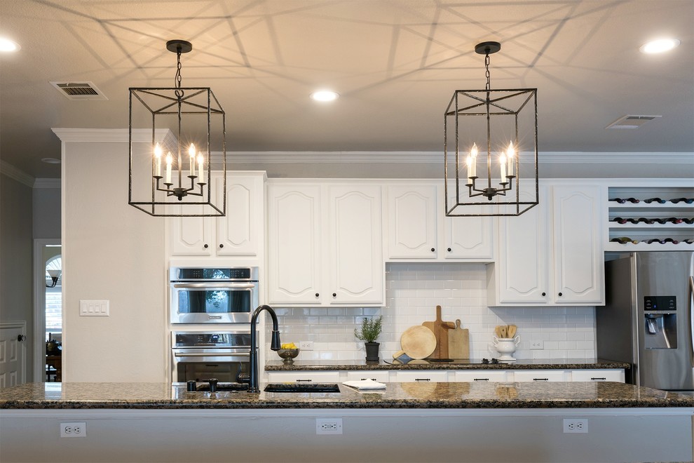 Large transitional galley medium tone wood floor open concept kitchen photo in Dallas with an undermount sink, white cabinets, granite countertops, white backsplash, subway tile backsplash, stainless steel appliances and two islands