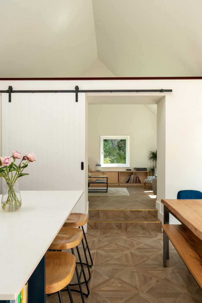На фото: большая гостиная-столовая в скандинавском стиле с белыми стенами, паркетным полом среднего тона, коричневым полом и кессонным потолком