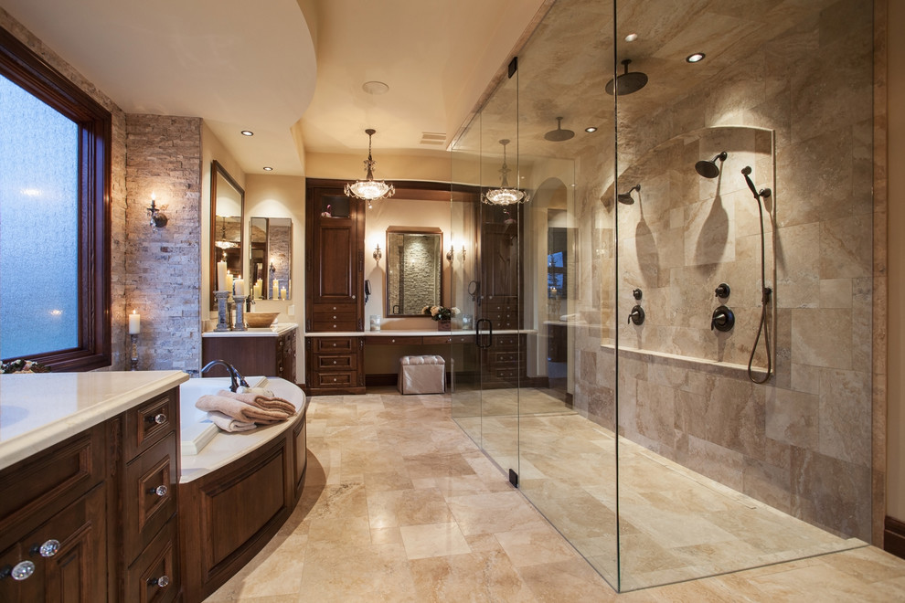 Design ideas for a large mediterranean master bathroom in Calgary with recessed-panel cabinets, dark wood cabinets, a drop-in tub, a double shower, beige tile, stone tile, beige walls, marble floors, an undermount sink, engineered quartz benchtops, beige floor and a hinged shower door.