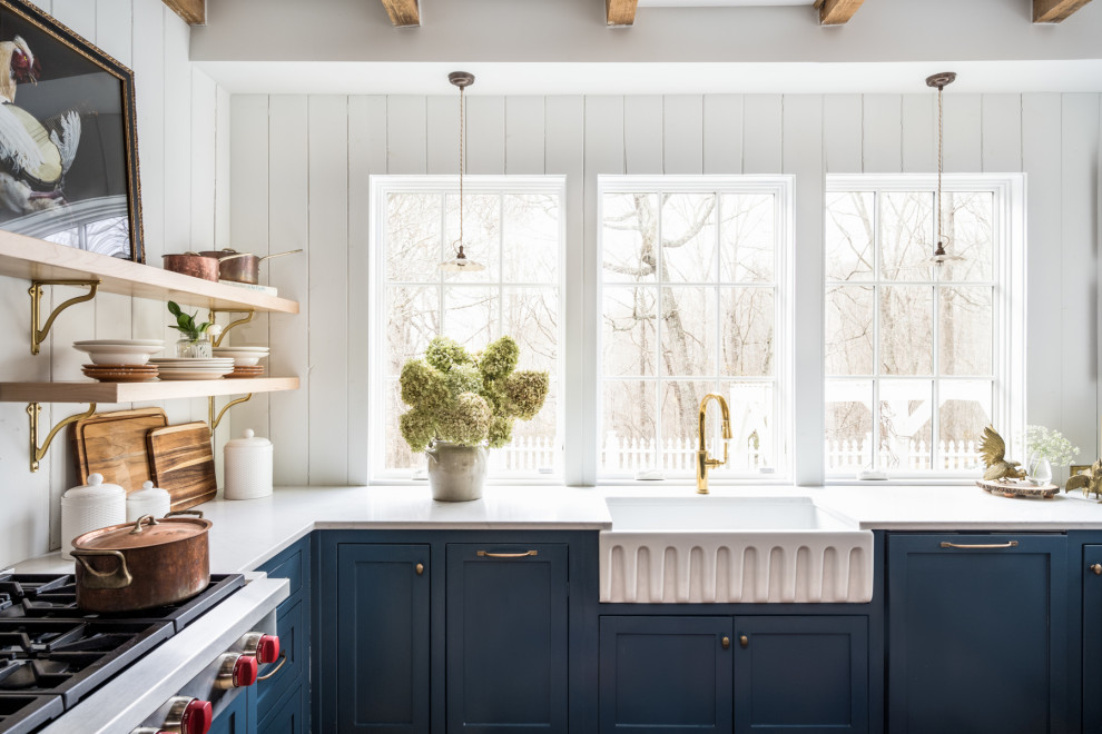 Mid-sized country u-shaped separate kitchen in Nashville with a farmhouse sink, beaded inset cabinets, blue cabinets, quartz benchtops, white splashback, timber splashback, stainless steel appliances, light hardwood floors, with island, yellow floor, white benchtop and exposed beam.