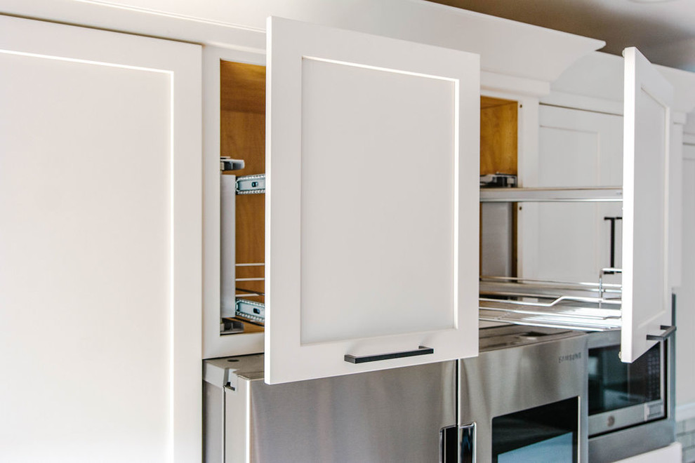 Inspiration for a mid-sized transitional l-shaped medium tone wood floor and brown floor eat-in kitchen remodel in Omaha with a farmhouse sink, shaker cabinets, white cabinets, quartzite countertops, white backsplash, subway tile backsplash, stainless steel appliances, an island and white countertops
