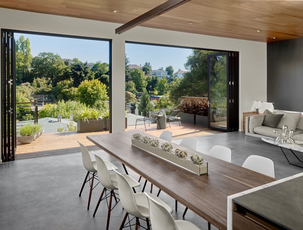 Photo of a mid-sized midcentury open plan dining in San Francisco with white walls, concrete floors and no fireplace.