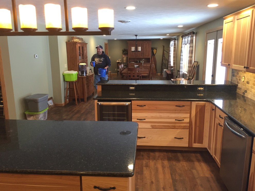 Example of a large mountain style l-shaped dark wood floor eat-in kitchen design with a double-bowl sink, flat-panel cabinets, light wood cabinets, granite countertops, brown backsplash, stone tile backsplash, stainless steel appliances and an island