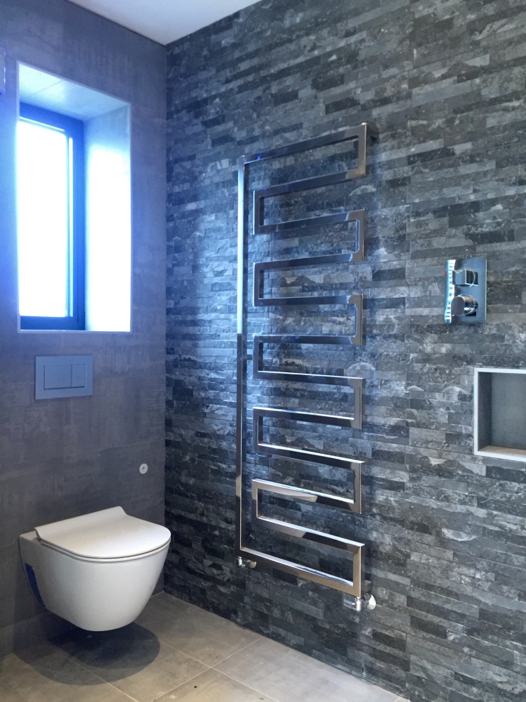 Bild på ett stort industriellt en-suite badrum, med luckor med profilerade fronter, svarta skåp, våtrum, en vägghängd toalettstol, grå kakel, porslinskakel, grå väggar, klinkergolv i porslin, ett väggmonterat handfat, grått golv och dusch med skjutdörr