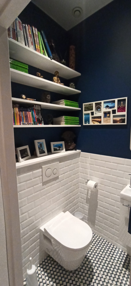 Réalisation d'un petit WC suspendu design avec un carrelage blanc, un carrelage métro, un mur bleu, carreaux de ciment au sol, un lavabo encastré, un plan de toilette en bois, un sol multicolore et un plan de toilette blanc.