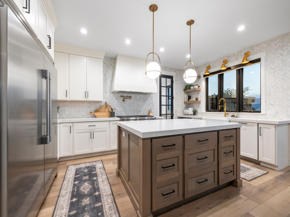 Large transitional u-shaped open plan kitchen in Other with a farmhouse sink, shaker cabinets, light wood cabinets, quartz benchtops, white splashback, marble splashback, stainless steel appliances, light hardwood floors, multiple islands, brown floor and white benchtop.
