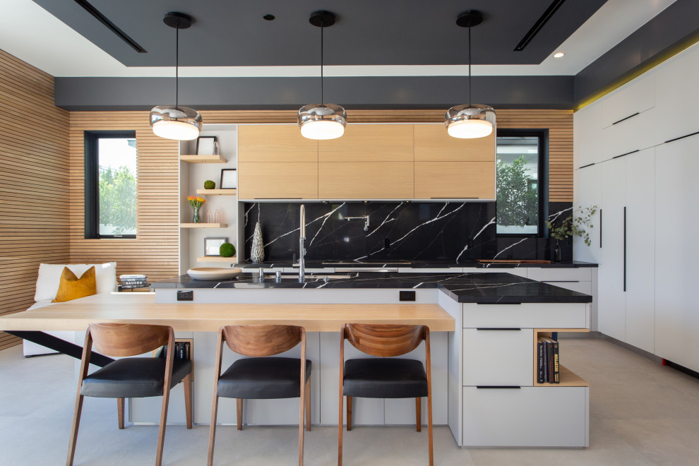 Expansive contemporary l-shaped kitchen in Los Angeles with an undermount sink, flat-panel cabinets, white cabinets, black splashback, panelled appliances, porcelain floors, with island, grey floor and grey benchtop.