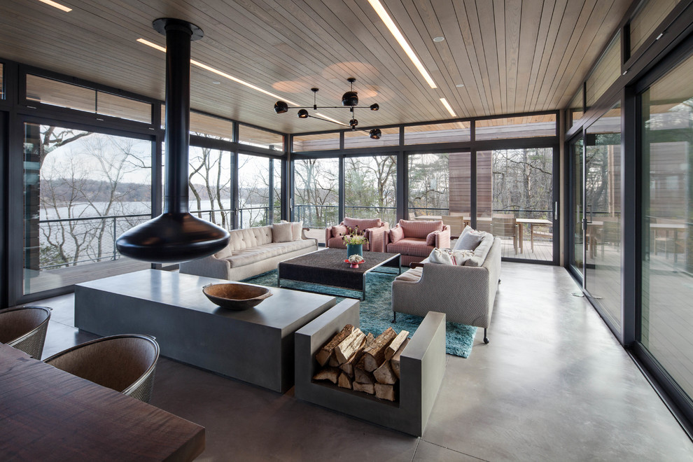 Contemporary open concept living room in New York with a hanging fireplace, concrete floors and no tv.
