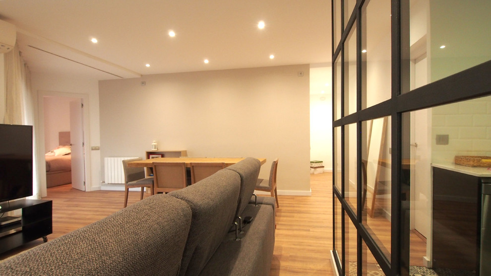 Imagen de sala de estar abierta industrial de tamaño medio con paredes beige, suelo de madera en tonos medios, televisor independiente y suelo marrón