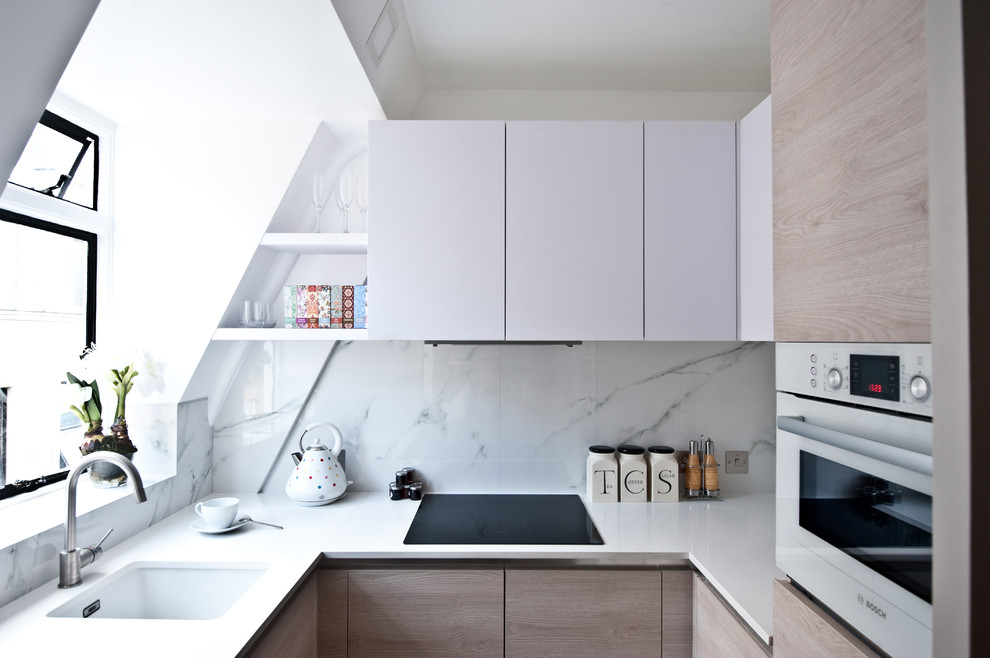 Small contemporary u-shaped kitchen in London with an undermount sink, flat-panel cabinets, white cabinets, quartz benchtops, white splashback, white appliances, no island and stone slab splashback.