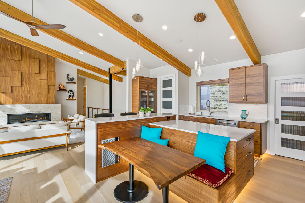 Example of a trendy l-shaped light wood floor, beige floor, exposed beam and vaulted ceiling open concept kitchen design in Seattle with an undermount sink, flat-panel cabinets, medium tone wood cabinets, white backsplash, stainless steel appliances, an island and white countertops