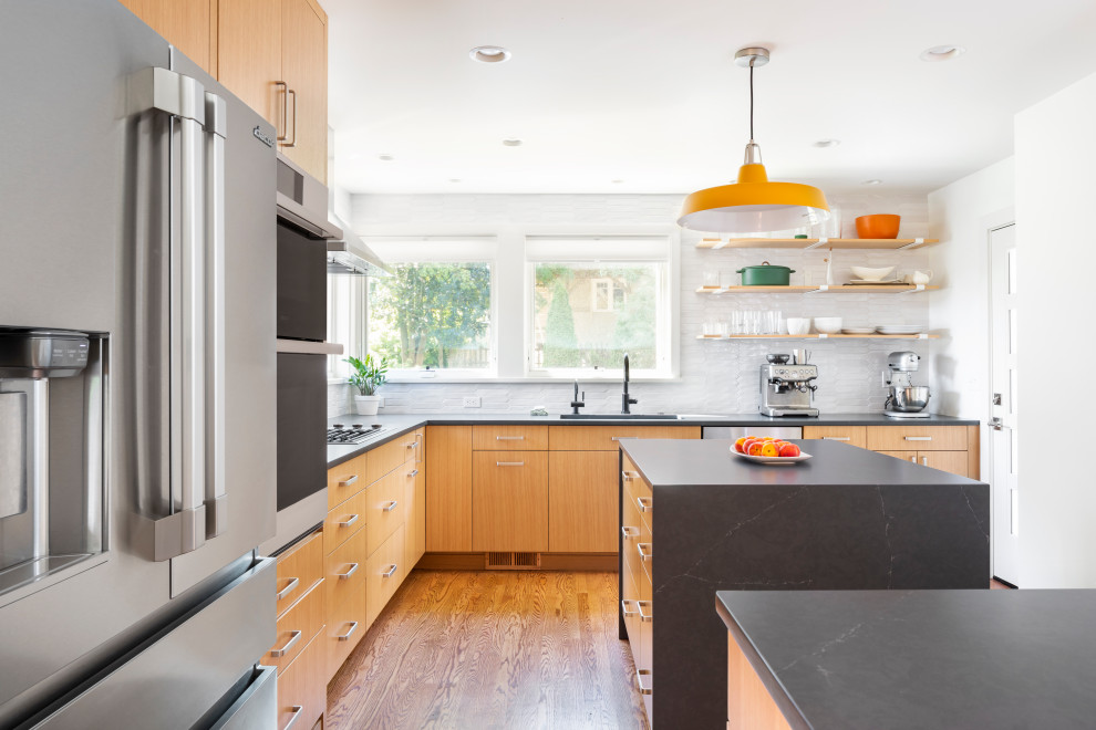 Design ideas for a mid-sized midcentury l-shaped separate kitchen in Seattle with flat-panel cabinets, medium wood cabinets, with island, an undermount sink, soapstone benchtops, white splashback, ceramic splashback, stainless steel appliances, medium hardwood floors and black benchtop.