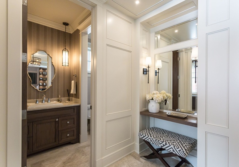 This is an example of a mid-sized traditional powder room in Calgary with recessed-panel cabinets, dark wood cabinets, brown walls, travertine floors and a drop-in sink.