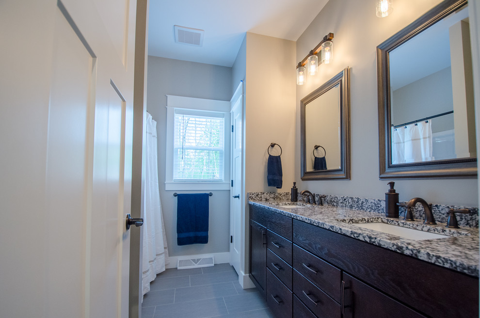 Example of a mid-sized transitional tub/shower combo design with shaker cabinets, dark wood cabinets, gray walls, an undermount sink and granite countertops