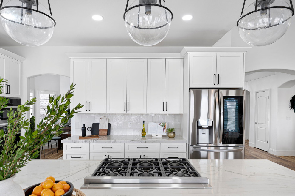 Kitchen - transitional vinyl floor and brown floor kitchen idea with a farmhouse sink, shaker cabinets, white cabinets, quartzite countertops, white backsplash and stainless steel appliances