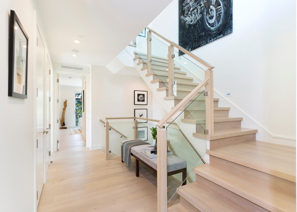 This is an example of a mid-sized modern wood l-shaped staircase in Miami with glass risers and wood railing.