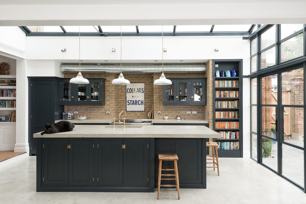 Design ideas for a transitional kitchen in London with glass-front cabinets, blue cabinets, concrete floors and with island.