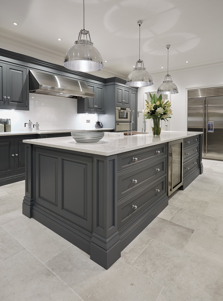 Design ideas for a mid-sized traditional galley separate kitchen in Manchester with a farmhouse sink, raised-panel cabinets, grey cabinets, solid surface benchtops, white splashback, ceramic splashback, stainless steel appliances, marble floors and with island.
