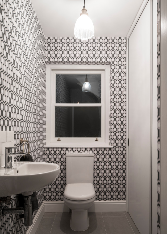 This is an example of a contemporary powder room in Other with a one-piece toilet, black walls, a wall-mount sink, grey floor and white benchtops.