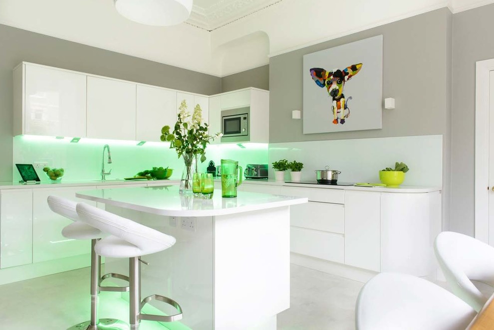 Mid-sized contemporary eat-in kitchen in Other with an undermount sink, flat-panel cabinets, white cabinets, white splashback, stainless steel appliances, with island, grey floor and white benchtop.
