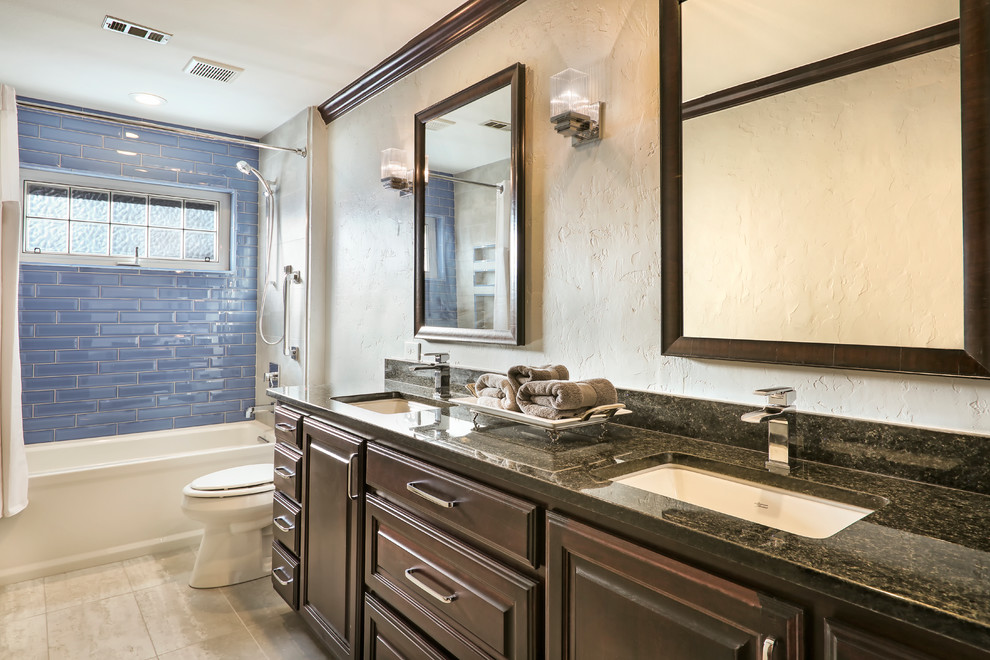 Mid-sized contemporary 3/4 bathroom in Other with raised-panel cabinets, dark wood cabinets, an alcove tub, a shower/bathtub combo, a two-piece toilet, blue tile, glass tile, beige walls, ceramic floors, an undermount sink, granite benchtops, beige floor and a shower curtain.