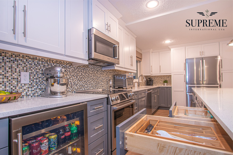 Modern inredning av ett mellanstort vit vitt kök, med en enkel diskho, skåp i shakerstil, grå skåp, bänkskiva i kvarts, flerfärgad stänkskydd, stänkskydd i glaskakel, rostfria vitvaror, vinylgolv, en köksö och brunt golv