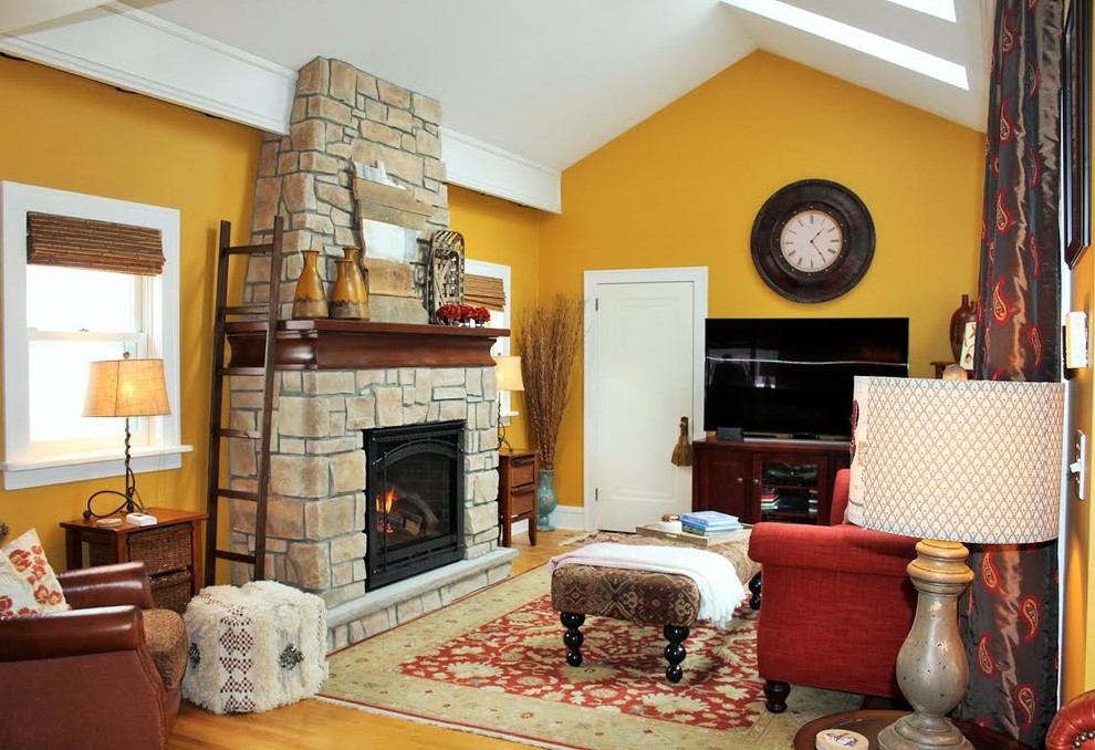 Inspiration for a mid-sized arts and crafts formal open concept living room in Minneapolis with yellow walls, medium hardwood floors, a standard fireplace, a stone fireplace surround, a freestanding tv and beige floor.