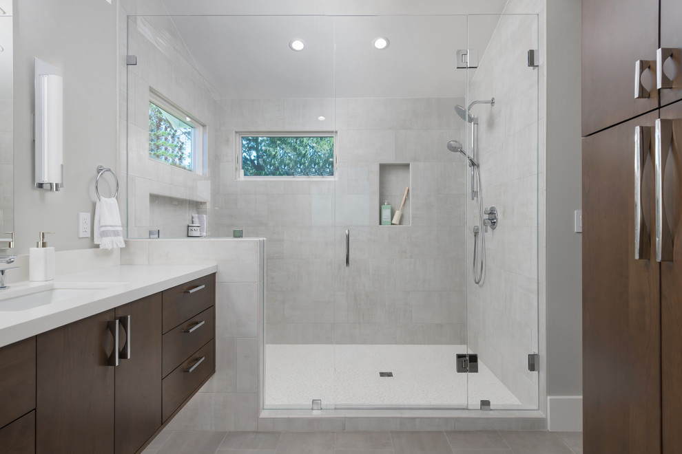 This is an example of a contemporary master bathroom in San Francisco with flat-panel cabinets, an alcove shower, a one-piece toilet, gray tile, ceramic tile, grey walls, ceramic floors, an undermount sink, engineered quartz benchtops, grey floor, a hinged shower door, white benchtops and dark wood cabinets.