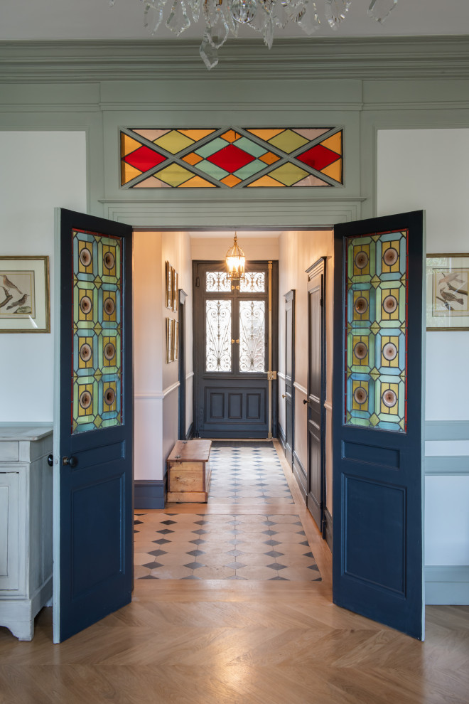 Large transitional foyer in Paris with white walls, a double front door and a blue front door.