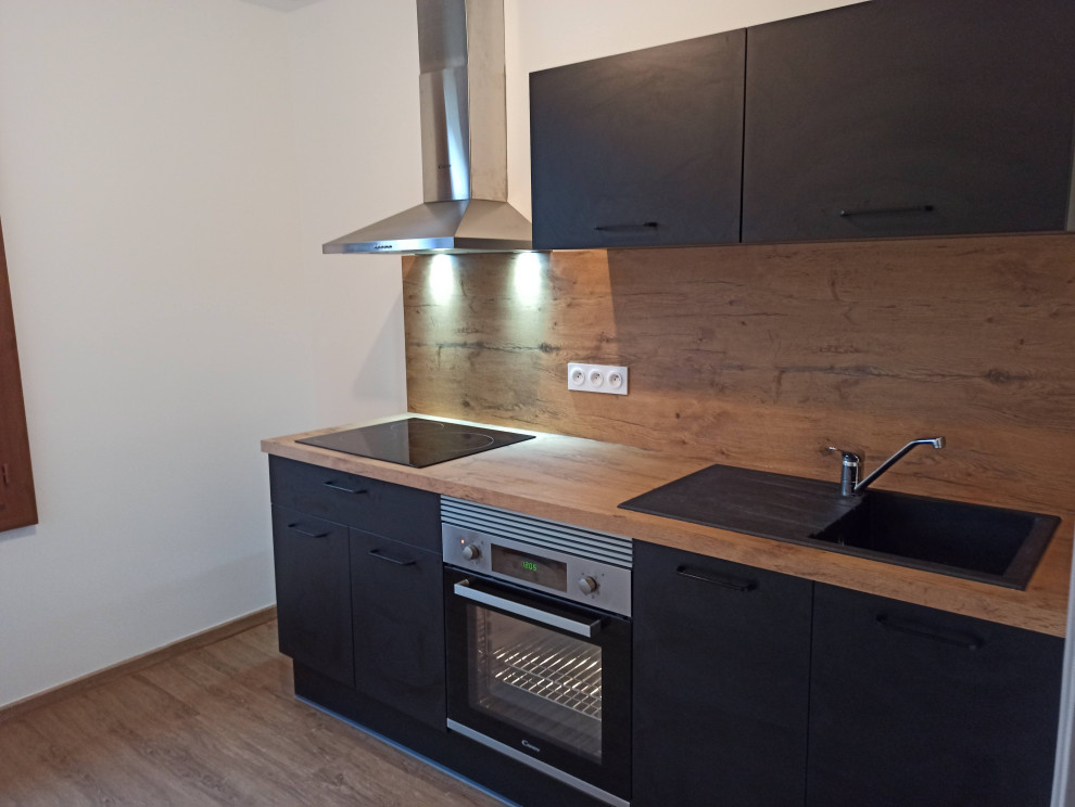 Photo of a mid-sized modern single-wall separate kitchen in Other with black cabinets, laminate benchtops, brown splashback, vinyl floors, brown floor and brown benchtop.