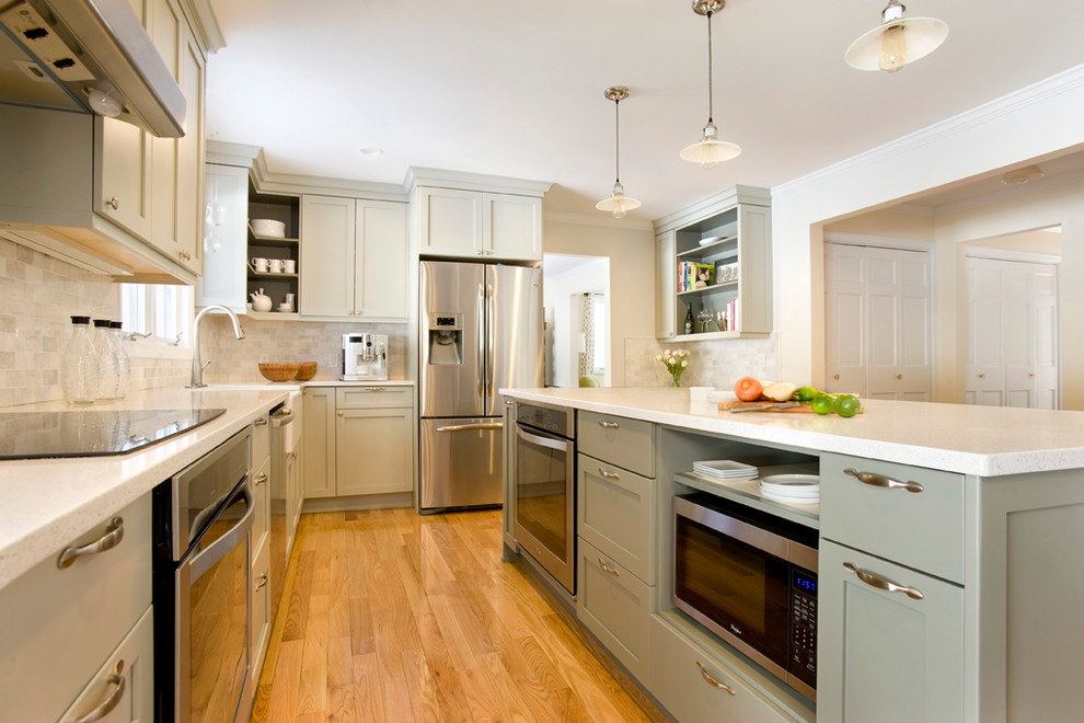 Design ideas for a mid-sized transitional l-shaped kitchen in Boston with a farmhouse sink, shaker cabinets, grey cabinets, recycled glass benchtops, white splashback, stone tile splashback, stainless steel appliances, light hardwood floors and with island.