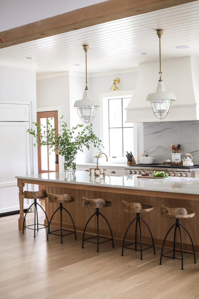 Inspiration for a beach style l-shaped kitchen in Chicago with a farmhouse sink, stainless steel appliances, light hardwood floors, with island, beige floor and white benchtop.