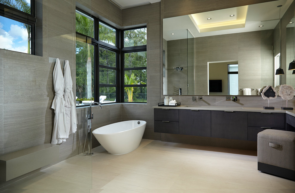 Photo of a contemporary master bathroom in Miami with flat-panel cabinets, dark wood cabinets, a freestanding tub, a curbless shower, gray tile and an open shower.