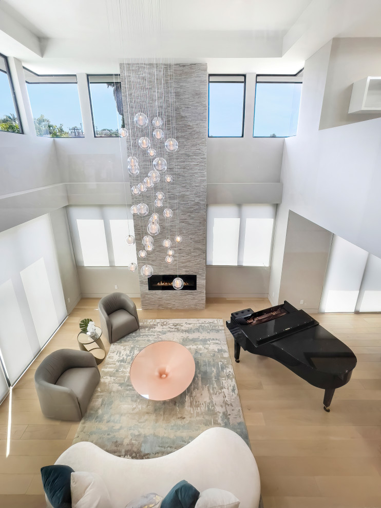 Aménagement d'un grand salon moderne ouvert avec une salle de musique, un mur gris, parquet clair, un manteau de cheminée en pierre, un sol beige et un plafond décaissé.