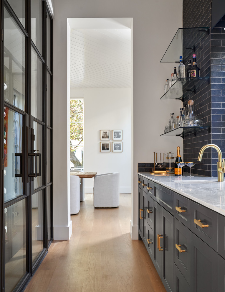 Beverly | 2018 - Mid-sized transitional galley concrete floor and gray floor seated home bar photo in Dallas with an undermount sink, recessed-panel cabinets, gray cabinets, quartz countertops, brown backsplash, wood backsplash and white countertops