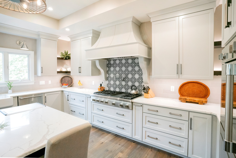 Open concept kitchen - transitional u-shaped medium tone wood floor, beige floor and tray ceiling open concept kitchen idea with an undermount sink, shaker cabinets, white cabinets, quartzite countertops, multicolored backsplash, porcelain backsplash, stainless steel appliances, an island and white countertops