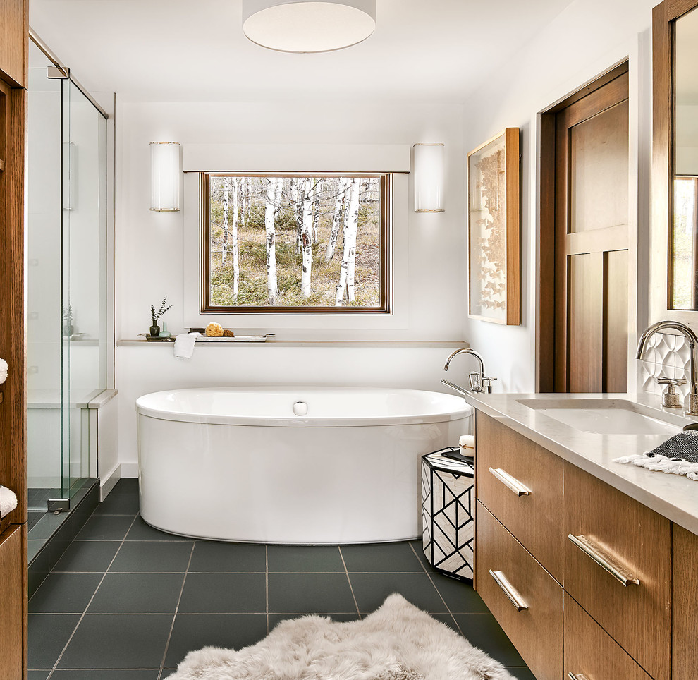 Design ideas for a country bathroom in Denver with flat-panel cabinets, medium wood cabinets, a freestanding tub, an alcove shower, white walls, an undermount sink, grey floor, a hinged shower door and grey benchtops.