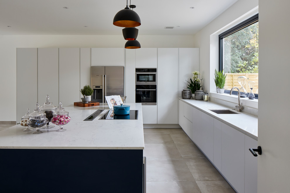 Photo of a modern kitchen in London with an undermount sink, flat-panel cabinets, white cabinets, solid surface benchtops, porcelain floors, with island, grey floor and white benchtop.