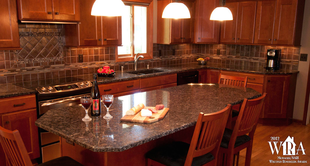 Eat-in kitchen - transitional l-shaped medium tone wood floor eat-in kitchen idea in Milwaukee with an undermount sink, recessed-panel cabinets, dark wood cabinets, granite countertops, gray backsplash, porcelain backsplash, stainless steel appliances and an island