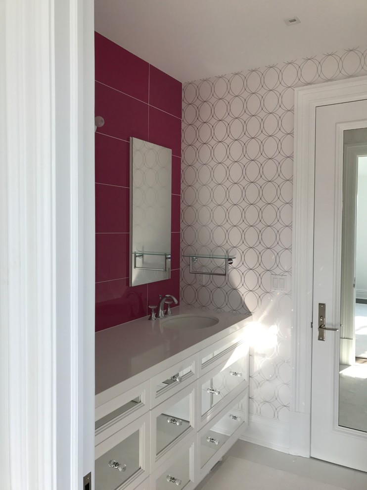 This is an example of a mid-sized transitional kids bathroom in New York with glass-front cabinets, white cabinets, pink tile, porcelain tile, white walls, porcelain floors, an undermount sink, engineered quartz benchtops, white floor and white benchtops.