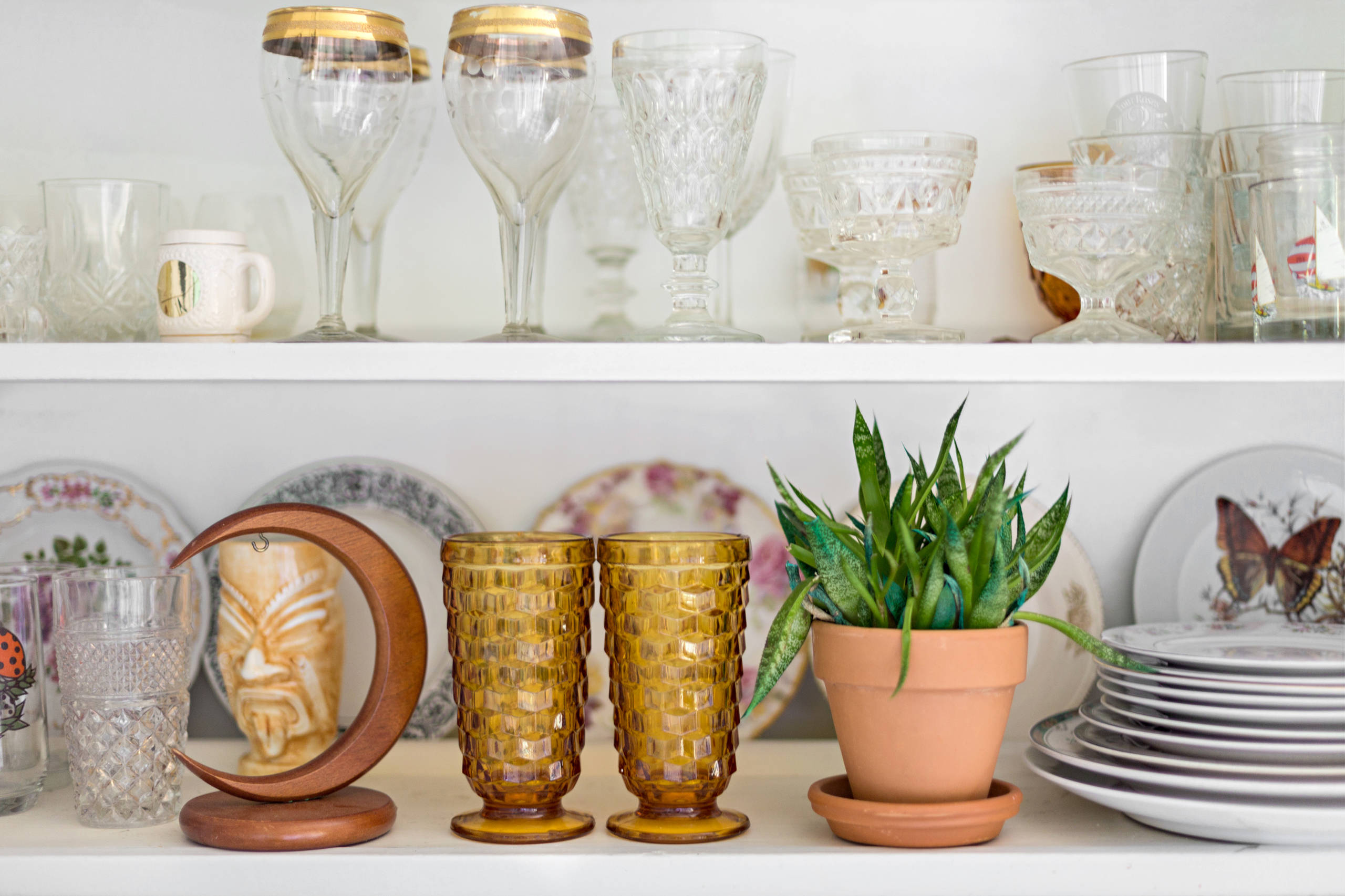 Vintage-looking glassware and ceramics displayed together on open shelving