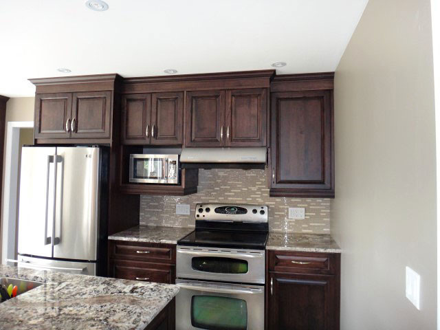 Inspiration for a large transitional galley eat-in kitchen remodel in Toronto with raised-panel cabinets, dark wood cabinets, granite countertops, multicolored backsplash, mosaic tile backsplash and an island