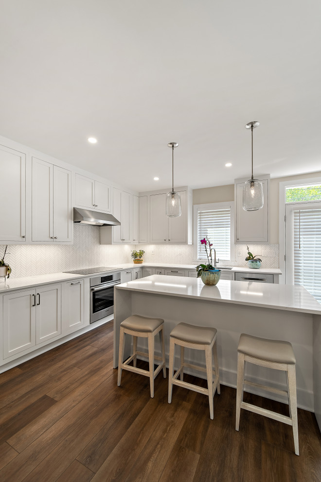 Example of a mid-sized transitional u-shaped brown floor eat-in kitchen design in DC Metro with a double-bowl sink, recessed-panel cabinets, white cabinets, quartzite countertops, ceramic backsplash, stainless steel appliances and an island