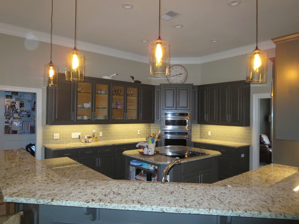 Eat-in kitchen - mid-sized transitional u-shaped eat-in kitchen idea in Austin with raised-panel cabinets, gray cabinets, granite countertops, beige backsplash, subway tile backsplash, stainless steel appliances and an island