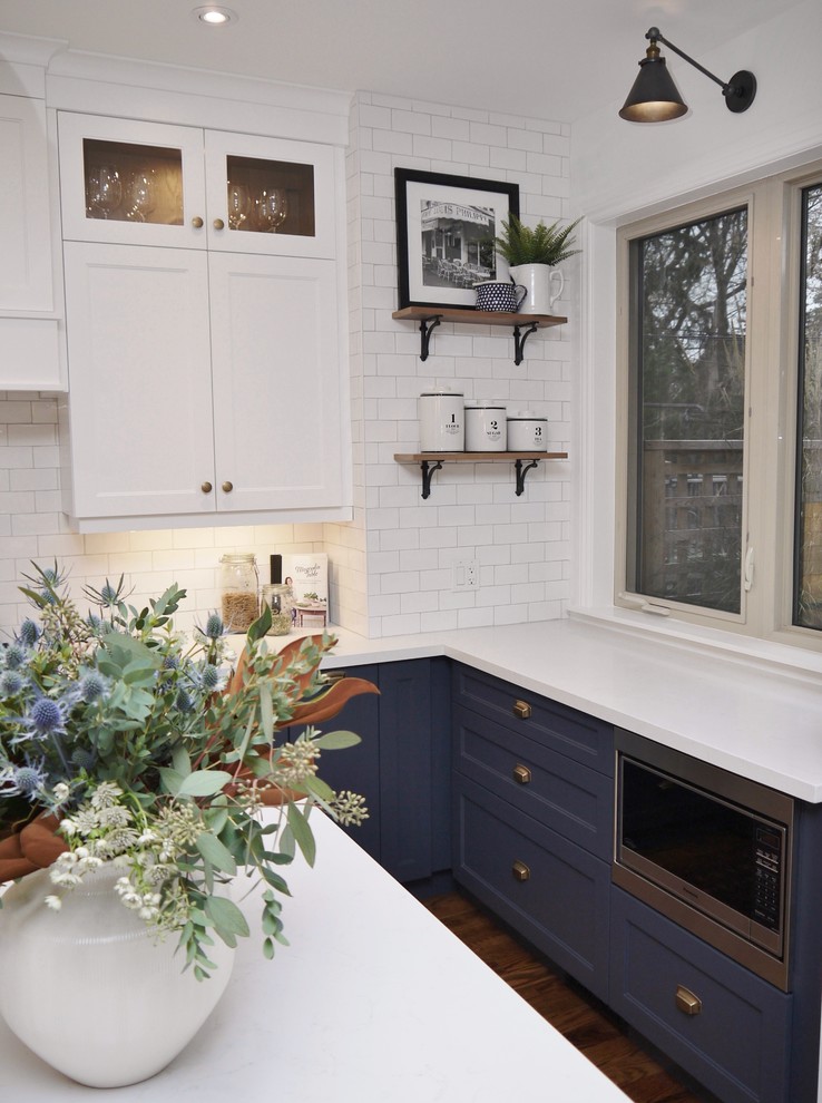Mid-sized transitional l-shaped medium tone wood floor and brown floor eat-in kitchen photo in Toronto with an undermount sink, shaker cabinets, blue cabinets, quartz countertops, white backsplash, subway tile backsplash, stainless steel appliances, an island and white countertops