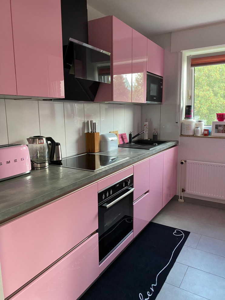 Idee per una cucina lineare minimal chiusa con ante rosa, elettrodomestici neri e nessuna isola