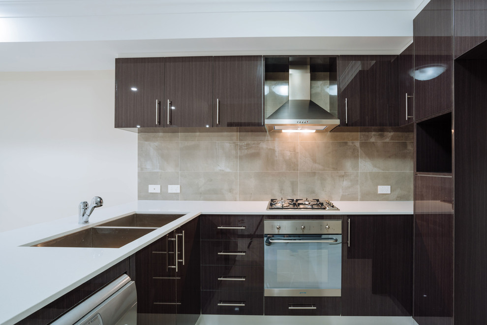 This is an example of a mid-sized contemporary u-shaped open plan kitchen in Perth with a double-bowl sink, flat-panel cabinets, dark wood cabinets, quartz benchtops, brown splashback, stainless steel appliances and porcelain floors.