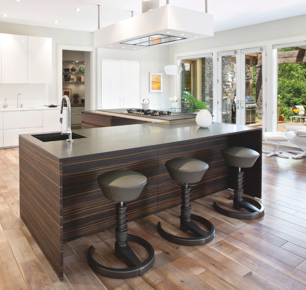 Inspiration for a mid-sized modern eat-in kitchen in Indianapolis with an undermount sink, medium wood cabinets, granite benchtops, white splashback, porcelain splashback, with island, flat-panel cabinets, panelled appliances, cork floors and brown floor.