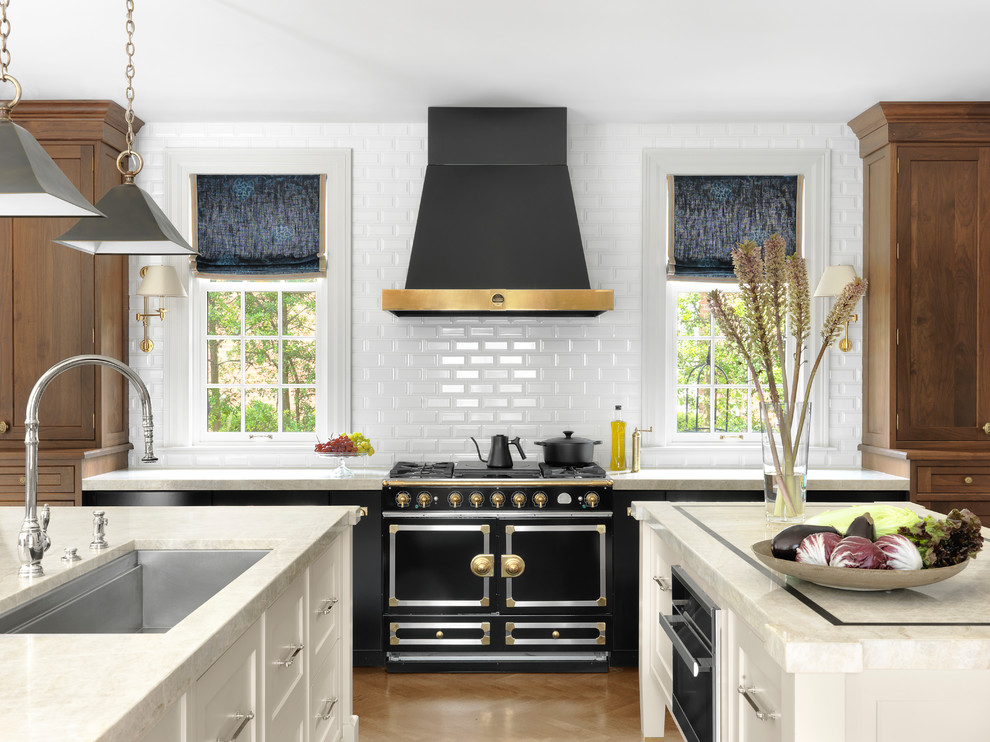 This is an example of a transitional kitchen in St Louis with an undermount sink, white splashback, subway tile splashback, black appliances, multiple islands, beige floor, white benchtop and quartzite benchtops.