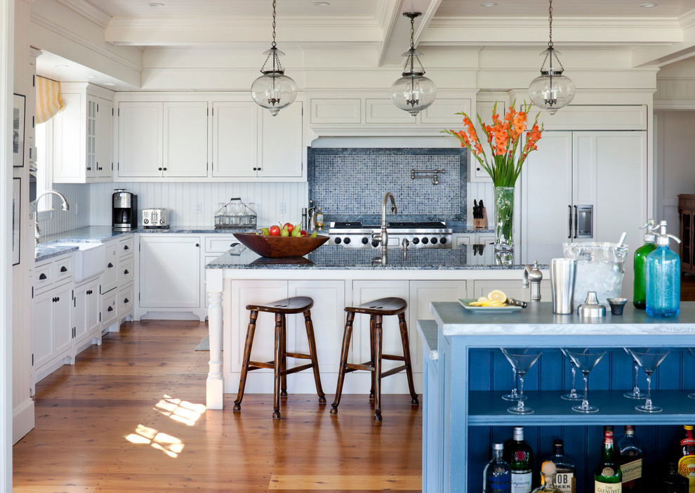 This is an example of a mid-sized beach style l-shaped separate kitchen in Boston with a farmhouse sink, shaker cabinets, white cabinets, blue splashback, mosaic tile splashback, stainless steel appliances, granite benchtops, dark hardwood floors, with island and brown floor.